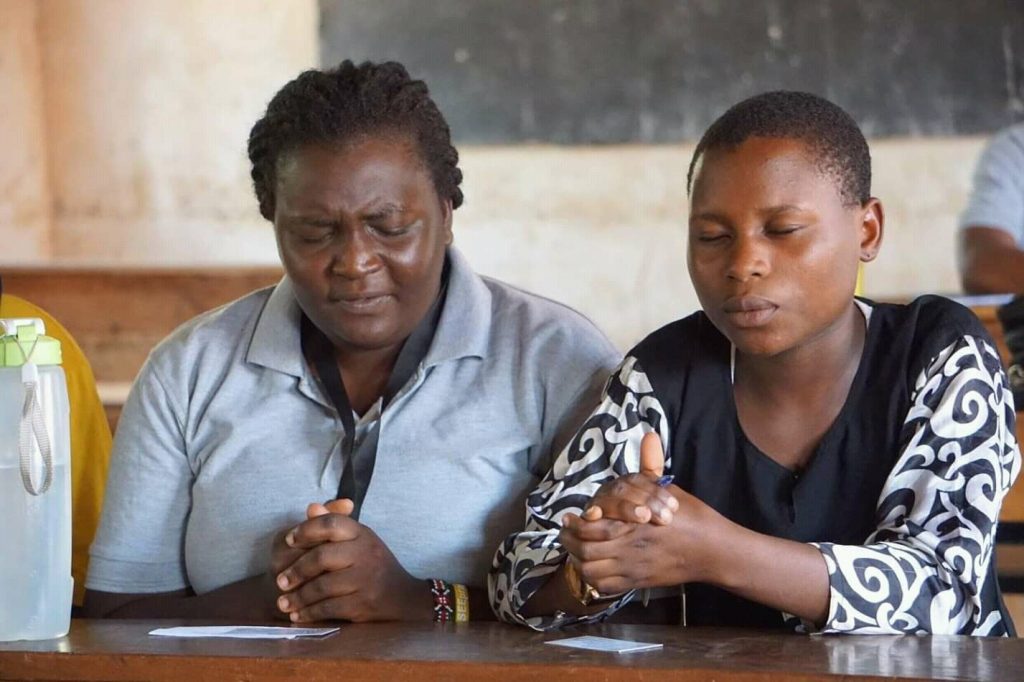 Dinah (left) praying with a student from one of the
schools